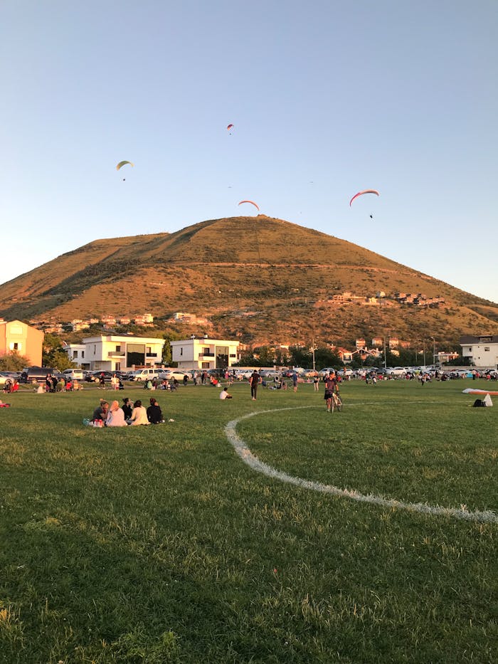 A scenic hill with paragliders and people relaxing on a sunny day.